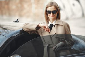 stylish woman standing near open door of modern car