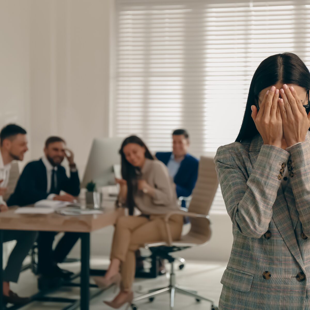 Woman standing with her hands to her face whist other colleagues look on