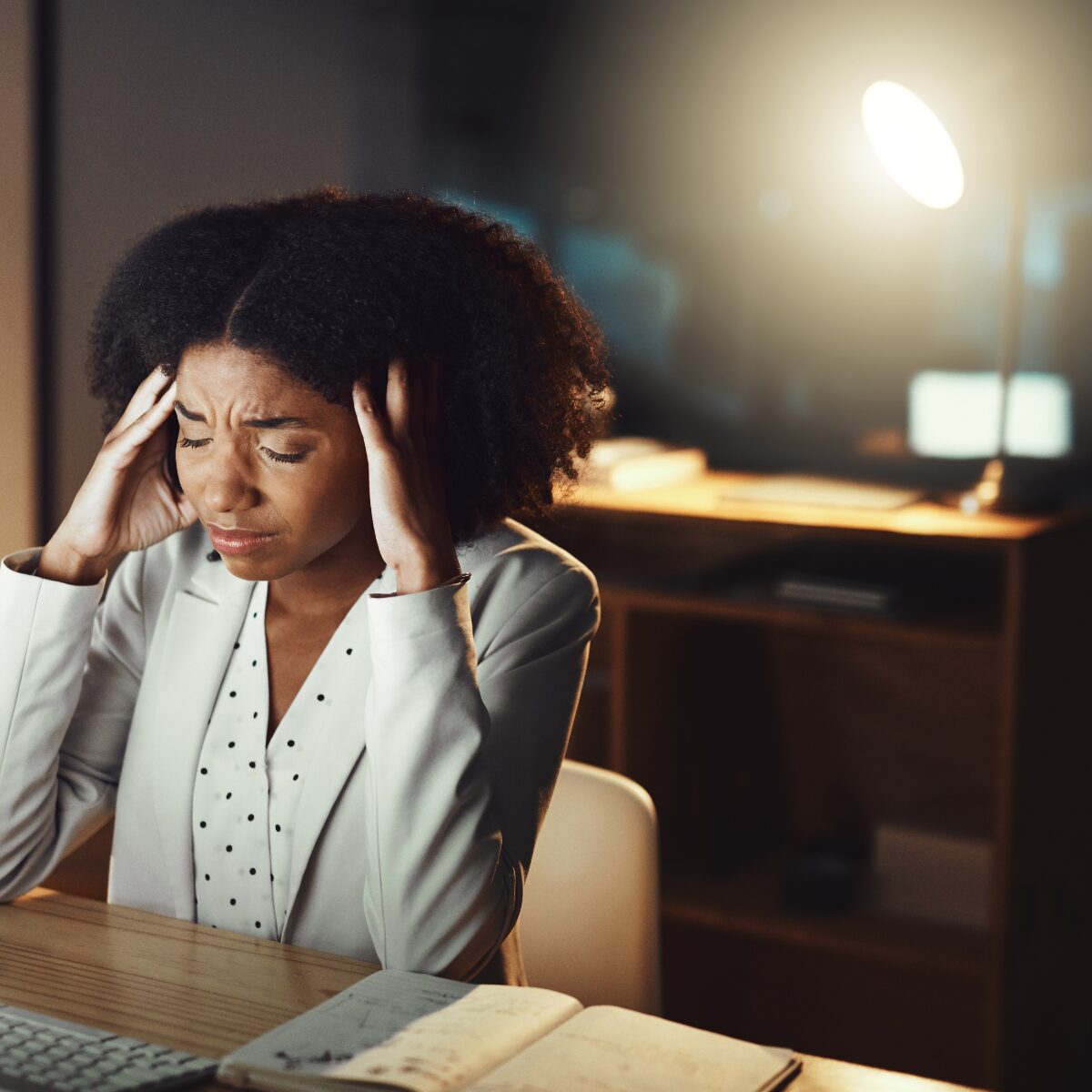 Woman sat at her computer with her head in her hands coping with a restructure