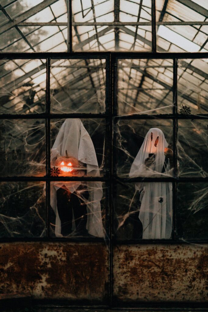 People Wearing Ghost Halloween Costumes in a Greenhouse carrying a pumpkin